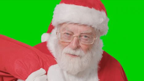 Close-Up-Shot-of-Santa-Walking-Into-and-Out-of-Frame-Holding-Sack-with-Green-Screen
