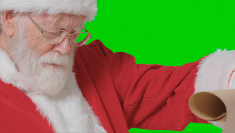 Nahaufnahme-Von-Weihnachtsmannhänden,-Die-Eine-Papierrolle-Vor-Einem-Grünen-Bildschirm-Halten