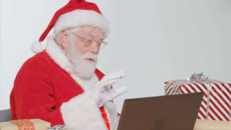 Mittlere-Aufnahme-Des-Weihnachtsmanns,-Der-über-Einen-Laptop-Videoanruf-Spricht