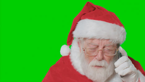 Close-Up-Shot-of-Santa-Talking-On-Mobile-Phone-In-Front-of-Green-Screen