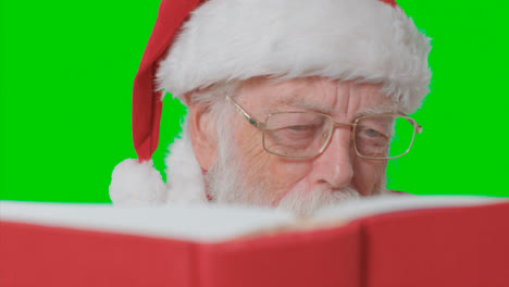 Close-Up-Shot-of-Santa-Reading-Red-Book-In-Front-of-Green-Screen