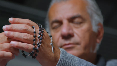 Low-Angle-Shot-of-Senior-Man-Praying-with-Rosary-Beads