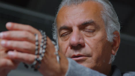 Low-Angle-Shot-of-a-Senior-Man-Praying-with-Rosary-Beads