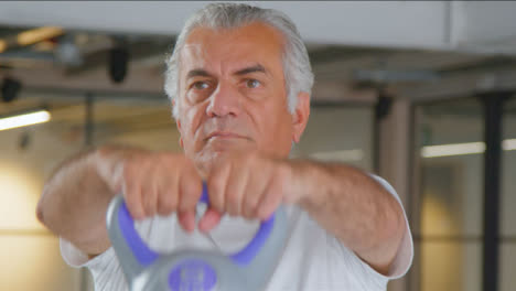 Close-Up-Shot-of-a-Senior-Man-Using-Kettle-Weight-in-Gym
