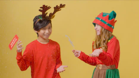 Two-Happy-Children-Holding-Christmas-Signs-Catch-Falling-Snow