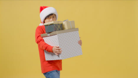 Boy-Walking-to-Camera-Holding-Christmas-Presents