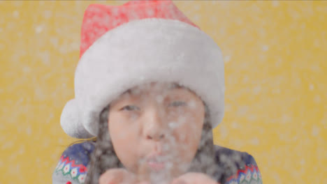 Child-in-Santa-Hat-Blows-Snow-at-Camera