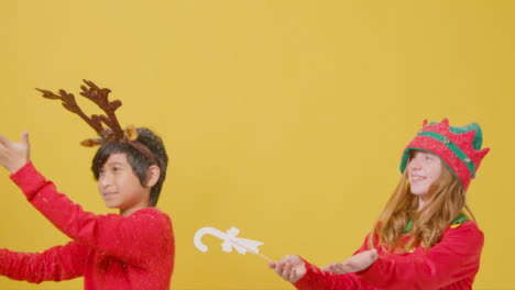 Two-Festive-Children-Holding-Christmas-Signs-Catch-Falling-Snow