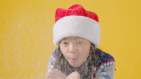 Festive-Boy-in-Santa-Hat-Blows-Snow