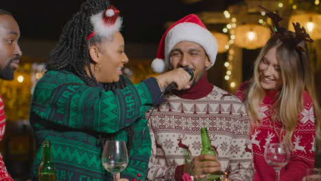 Sliding-Shot-of-Group-of-Friends-Singing-Karaoke-During-Christmas-Celebrations