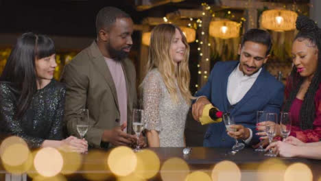 Foto-Deslizante-De-Amigos-Vertiendo-Champán-Durante-Las-Celebraciones-De-Año-Nuevo-En-Un-Bar.