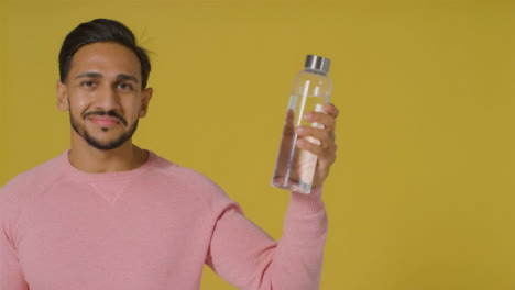 Portrait-Shot-of-Young-Man-Holding-Up-Bottle-with-Copy-Space