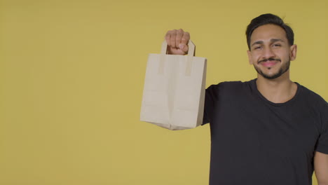 Portrait-Shot-of-Young-Man-Holding-Up-Paper-Bag