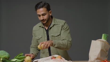 Mid-Shot-of-Young-Man-Unpacking-Vegetables-at-Kitchen-Workstation