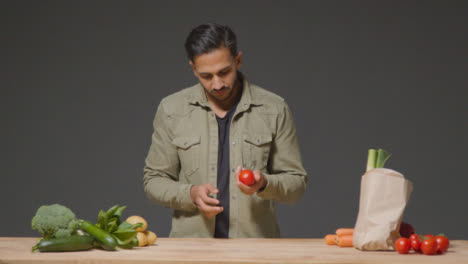 Wide-Shot-of-a-Young-Man-Inspecting-a-Tomato