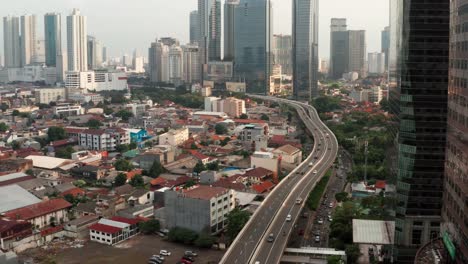 Drohnenschuss,-Der-An-Einem-Gebäude-Vorbeifliegt-Und-Einen-Jakarta-Highway-Enthüllt
