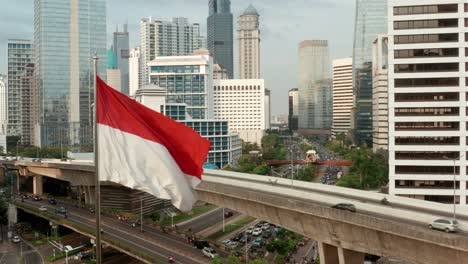 Drohnenschuss,-Der-Sich-Von-Der-Indonesischen-Flagge-Entfernt-Und-Die-Innenstadt-Von-Jakarta-Enthüllt