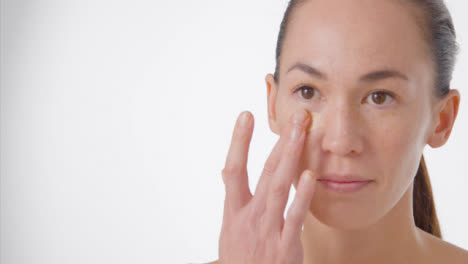 Close-Up-Shot-of-a-Young-Woman-Applying-Concealer-with-Copy-Space