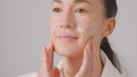 Close-Up-Shot-of-Young-Woman-Rubbing-Cream-on-Her-Face