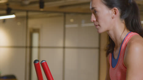 Tracking-Shot-of-a-Young-Woman-Working-Out-on-a-Bike-at-Gym