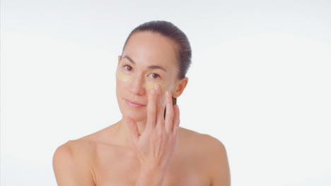 Mid-Shot-of-Young-Woman-Smiling-and-Applying-Concealer