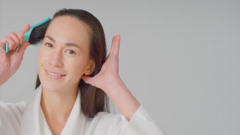 Mid-Shot-of-Young-Woman-Brushing-Her-Hair-and-Smiling