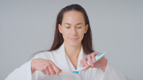 Mid-Shot-of-Woman-Putting-Toothpaste-on-Brush-