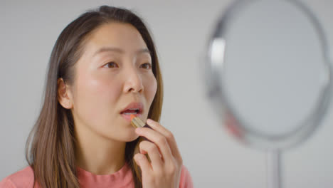 Close-Up-Shot-of-Woman-Applying-Lipstick