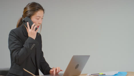 Medium-Shot-of-Businesswoman-Working-at-Desk-On-Phone