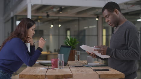 Mid-Shot-of-Woman-Working-and-Man-Looking-at-Paperwork