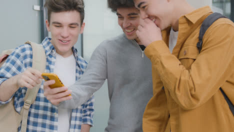 Pedestal-Shot-of-Students-Looking-and-Laughing-at-Smartphone-