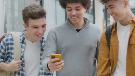 Tracking-Shot-of-Students-Looking-and-Laughing-at-Smartphone-
