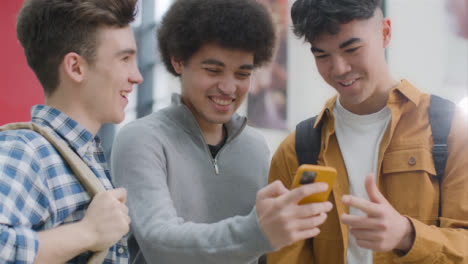 Tracking-Shot-of-Students-Laughing-at-Content-On-Smartphone
