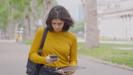 Tracking-Shot-of-Young-Student-Walking-Whilst-Looking-at-Her-Smartphone