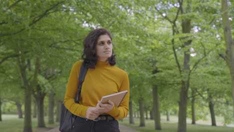 Tracking-Mid-Shot-of-Young-Woman-Walking-Through-Tree-Lined-Path