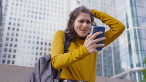 Low-Angle-Shot-of-Young-Woman-On-Smartphone-Celebrating