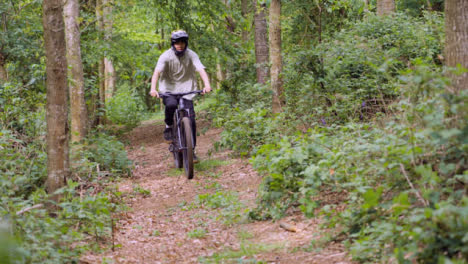 Zeitlupenaufnahme-Eines-Mannes-Auf-Dem-Mountainbike,-Der-Auf-Dem-Weg-Durch-Den-Wald-Radelt