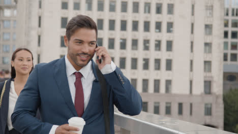 Hombre-De-Negocios-Al-Teléfono-Que-Viaja-A-Caminar-Por-La-Ciudad-Con-Bebida-Para-Llevar