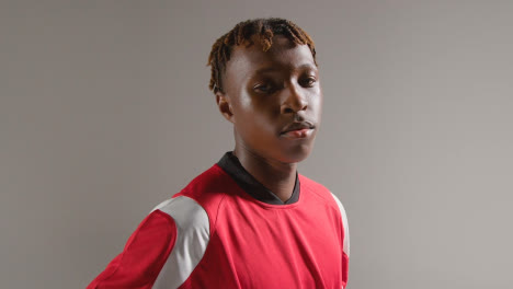 Studio-Portrait-Of-Young-Male-Footballer-Wearing-Club-Kit-With-Ball-Under-Arm-1