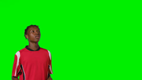 Studio-Shot-Of-Young-Male-Footballer-Wearing-Club-Kit-Controlling-Ball-With-Chest-And-Passing-Against-Green-Screen