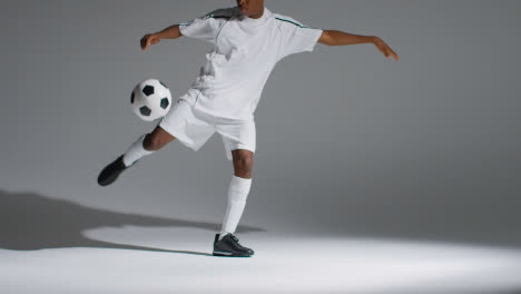 Studio-Shot-Of-Male-Footballer-Wearing-Club-Kit-Controlling-Ball-With-Chest-And-Shooting