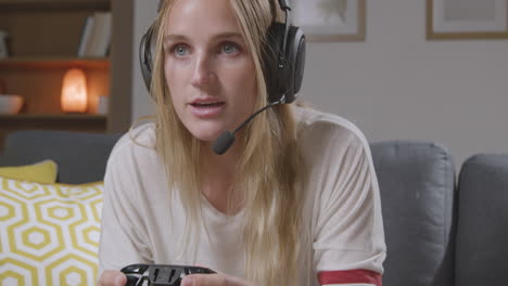Woman-Wearing-Headset-Sitting-On-Sofa-At-Home-Gaming-Online-3