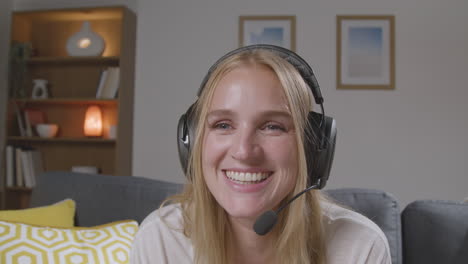 Woman-Wearing-Headset-Sitting-On-Sofa-At-Home-Gaming-Online-4