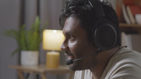 Man-Wearing-Headset-Sitting-On-Sofa-At-Home-Gaming-Online-4