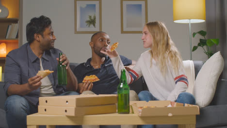 Multi-Cultural-Friends-Sitting-On-Sofa-At-Home-Eating-Takeaway-Pizza-Delivery-And-Drinking-Beer-4