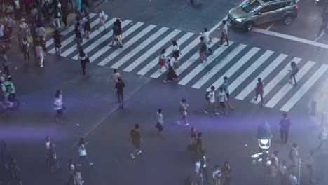 Alto-ángulo-de-la-toma-de-lapso-de-tiempo-del-paso-de-peatones-de-despegue-en-tiempo-mínimo-peatonal-de-Shibuya-famoso-con-multitudes-de-personas-que-cruzan-y-tráfico.-Noche-en-la-gran-ciudad.
