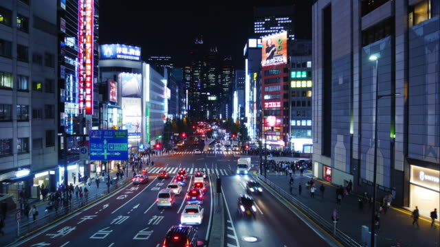 Zeitraffer-vieler-Fahrzeuge-und-Menschen-pendeln-entlang-einer-Straße-in-Tokio-Shinjuku-nachts.-Shinjuku-ist-ein-wichtiges-Handelszentrum,-der-verkehrsreichste-Bahnhof-der-Welt.