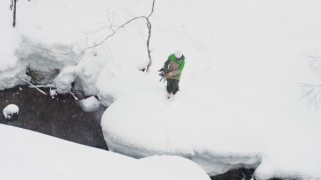 Snowboarder-peligroso-salto-sobre-Río-profundo-polvo-nieve-japonés-montañas
