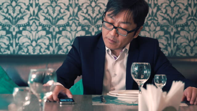 Hombre-asiático-en-traje-de-empresario-esperando-en-el-café-su-comida.-Largas-esperas-para-pedir.-Nervioso