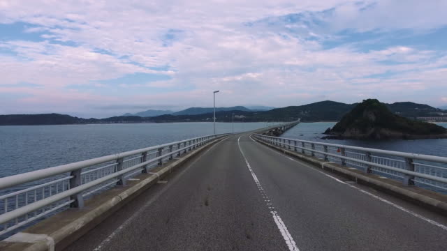 Ozean-\"Tsunoshima-Brücke\"-Schuss-leer,-gerade-Straße-überfahren